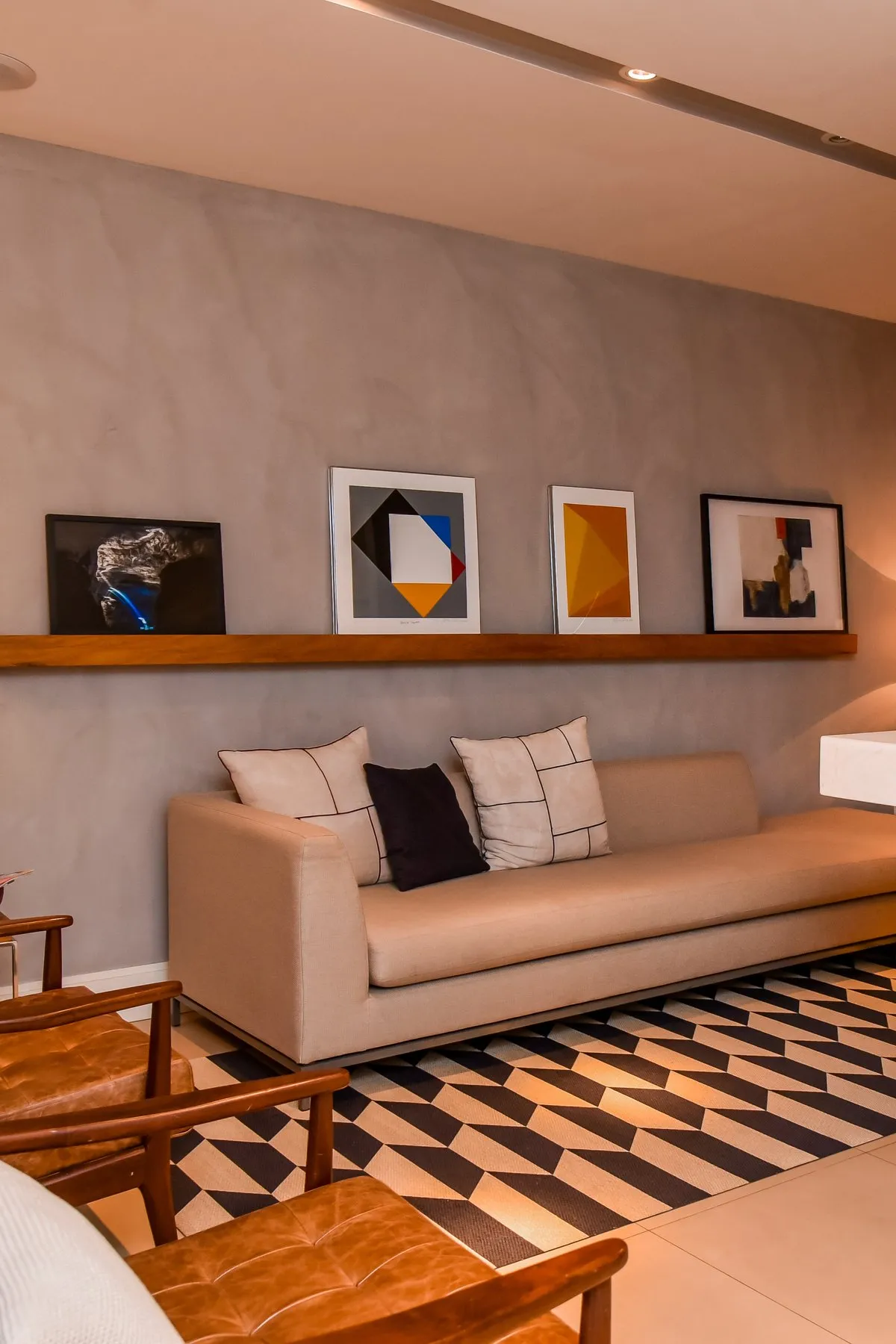 Sala de espera com sofá, poltronas de couro e quadros