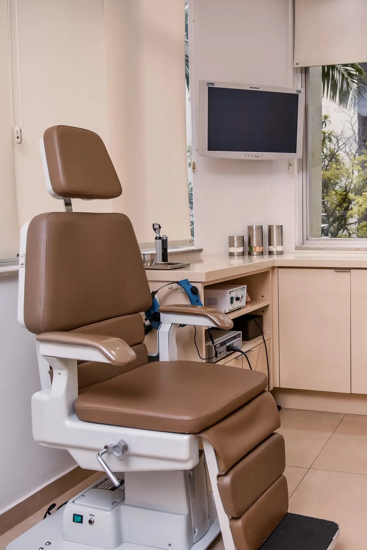 Sala de exame com cadeira otorrinolaringológica e equipamento de endoscopia